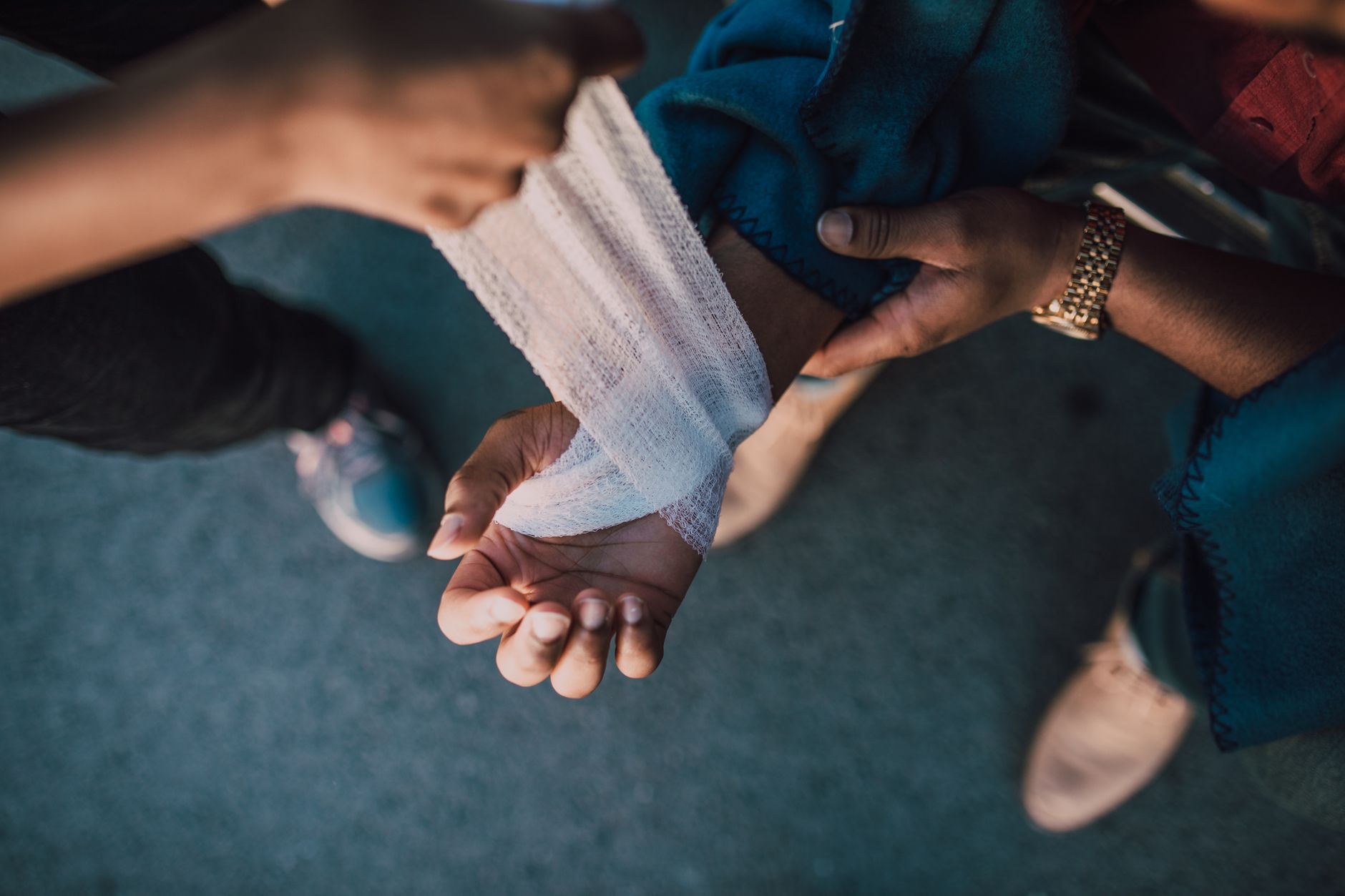 Hands wrapping a bandage around an injured wrist outdoors.